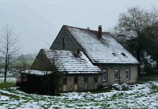Bauernhaus mit kleinem Stall in leicht verschneiter Winterlandschaft